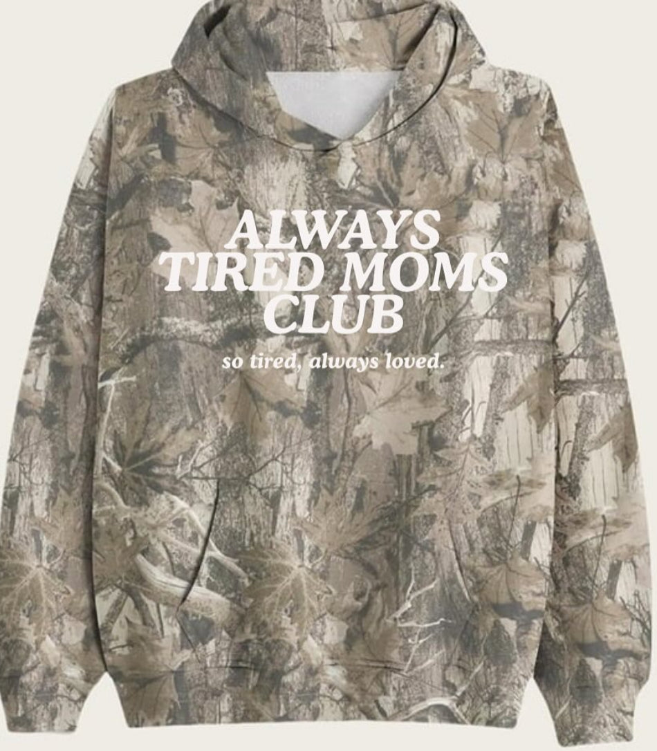 Camouflage hoodie with 'Always Tired Moms Club' text on a light background
